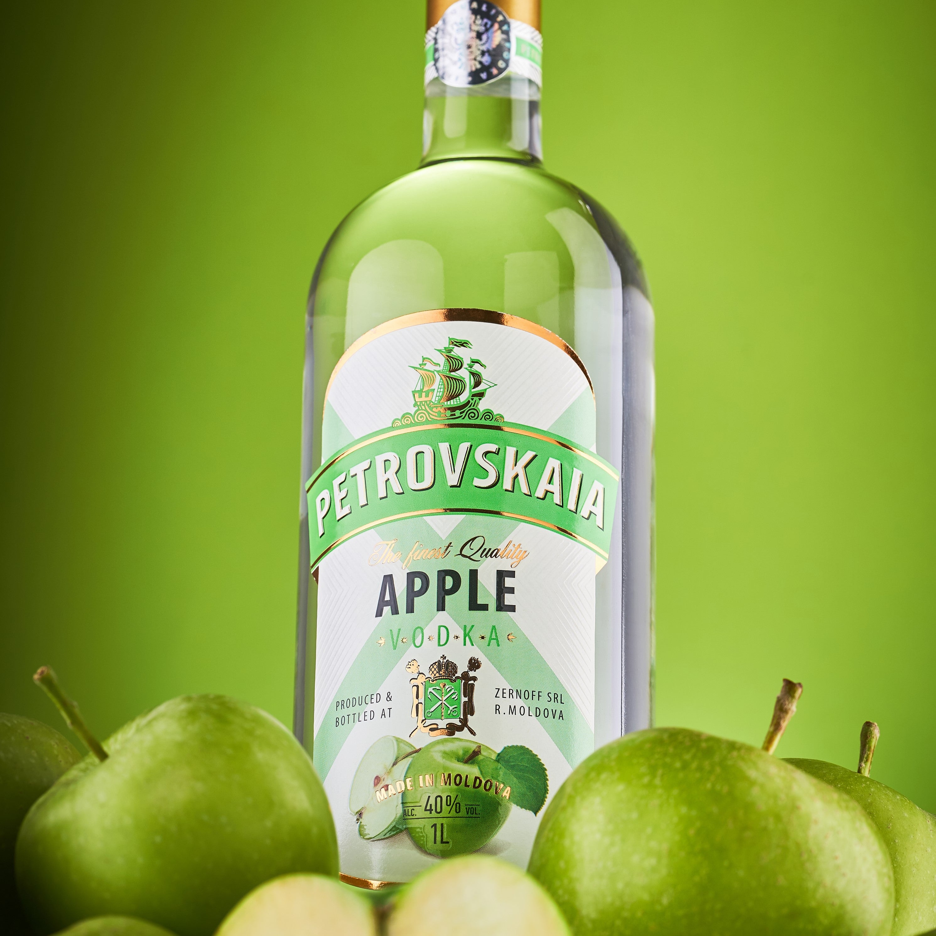 Petrovskaia Apple premium Vodka fles omringd door groene appels tegen een groene achtergrond.